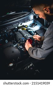 Mecánico enfocado a reparar autos. Desconectar el terminal de la batería del coche moderno. Fotografía vertical.