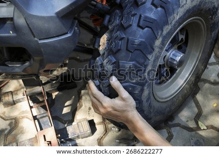 Focused mechanic hand changing large off road tire on vehicle. close up view of hands on process for automotive repair, maintenance, and service on lifted quad bike