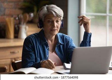 Focused Middle Aged Mature Woman Wearing Wireless Headphones, Involved In Online Communication With Teacher Using Computer Software Video Call Application, Older People And Distant Education Concept.