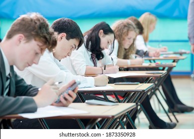 Focused middle school students with calculator taking examination at desks