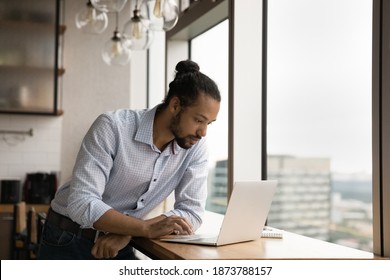 Focused millennial African American businessman look at laptop screen consult client or customer online. Serious young biracial man work on computer in office, browse wireless internet on gadget. - Powered by Shutterstock