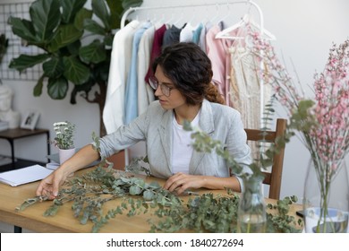 Focused millennial female designer make floral compositions or decorations on desk in cozy home office. Young Caucasian female florist arrange compose handmade bouquets for sale. Décor concept. - Shutterstock ID 1840272694
