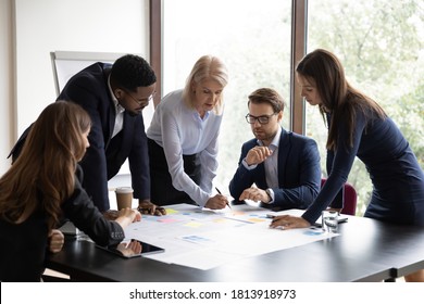 Focused multiracial businesspeople brainstorm analyze company financial documents at meeting together. Concentrated diverse colleagues talk discuss business project paperwork at briefing in office. - Shutterstock ID 1813918973