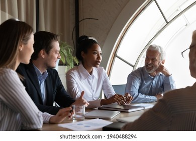 Focused multiracial businesspeople brainstorm at team meeting in modern office. Concentrated diverse multiethnic colleagues coworkers talk discuss business ideas at briefing. Teamwork concept.