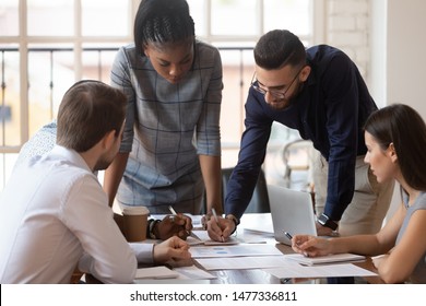 Focused multiracial corporate business team people brainstorm on marketing plan financial report gather at office table meeting, diverse serious colleagues group discuss paperwork engaged in teamwork - Shutterstock ID 1477336811