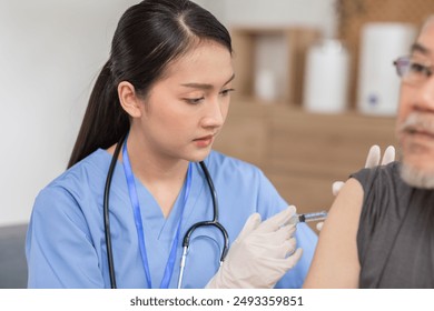  focused nurse in blue scrubs and wearing a stethoscope administers a vaccine to an elderly male patient. The nurse is wearing gloves and handling the syringe with care - Powered by Shutterstock