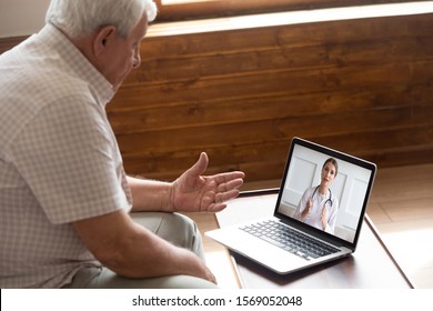 Focused older 80s male patient consulting with doctor via computer video call. Senior man looking at laptop screen, talking to therapist cardiologist online, older generation using modern technology.
