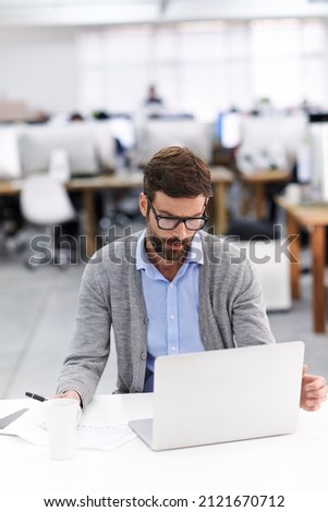 Focused on the finer details. Shot of a handsome young businessman using a laptop in a casual working environment.