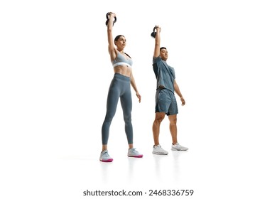 Focused on training man and woman performing kettlebell press exercise and demonstrate excellent form against white studio background. Concept of people in sport, healthy lifestyle, teamwork. Ad - Powered by Shutterstock