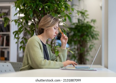 Focused Pensive Woman University Professor Preparing Lecture Material On Laptop In Light Cozy Library With Green Houseplants, Selective Focus. Scandinavial Middle-aged Female Getting Second Degree