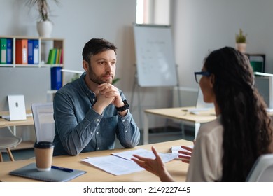 Focused personnel manager and young female job applicant communicarting on work interview at modern company office. Employment, headhunting, staff recruitment concept