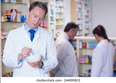 Focused Pharmacist Using Mortar And Pestle In The Pharmacy