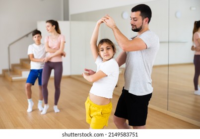 Focused Pre-teen Girl Exercising Dance Moves With Dad At Family Dance Class, Family Practicing Dance In Pair