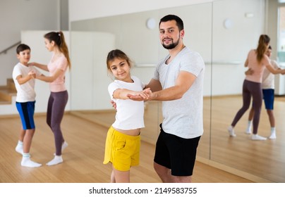 Focused Pre-teen Girl Exercising Dance Moves With Dad At Family Dance Class, Family Practicing Dance In Pair