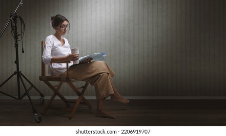 Focused Professional Actress Sitting On The Director's Chair And Reading A Play Script, Blank Copy Space