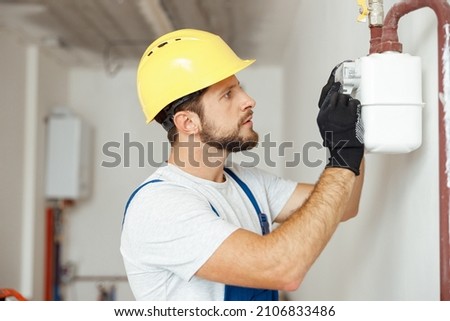 Focused professional heating fitter checking gas consumption at gas pipe and meter counter