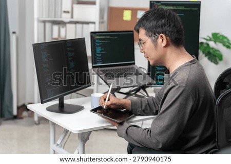 A focused professional programmer working on a modern desk with multiple computer screens, coding software, and a digital workspace in a well-organized office environment.
