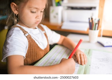 Focused Schoolgirl Writing and Learning at Home with Educational Tools - Powered by Shutterstock