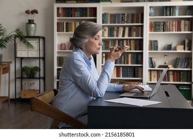 Focused Senior Business Woman Recording Audio Message On Mobile Phone At Office Workplace, Dictating Vocal Command To Virtual Assistant For Online Search, Using Voice Recognition App On Cellphone