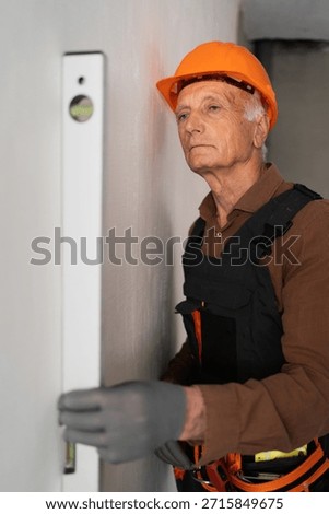 Focused Senior elderly builder using spirit level during building construction or renovation. construction professional at work. copy space