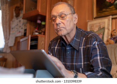 Focused senior man using tablet at home