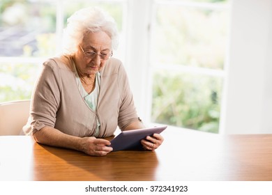 Focused Senior Woman Using Tablet At Home