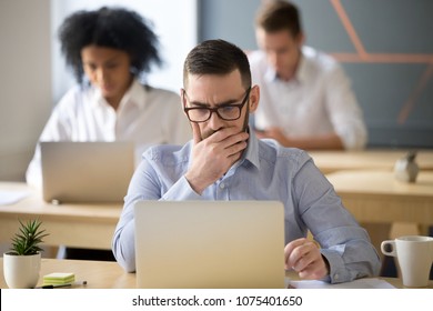 Focused serious businessman thinking of online task concerned about solving business problem working on laptop in coworking office, puzzled manager using computer worried by reading bad email news