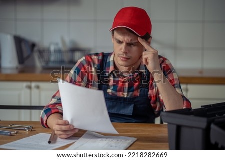 Focused serviceman dressed in workwear perusing installation instructions