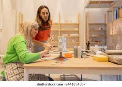 A focused session of two women painting geometric patterns on a ceramic vase at a craft workshop. - Powered by Shutterstock