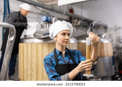 Focused skilled young female brewery worker using digital hydrometer for measuring craft beer density.. - Powered by Shutterstock