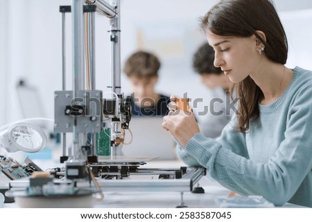 Focused smart female student using a 3D printer in the lab: education, technology and science concept