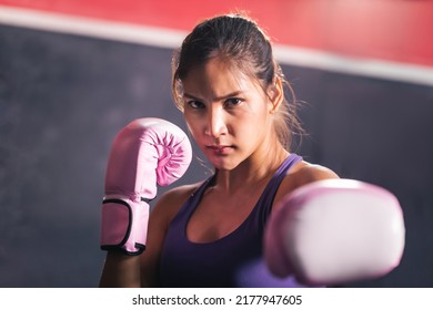 Focused sporty athlete Asian woman wearing pink punching gloves practicing boxing martial arts at the gym. Young fit attractive female with purple sportswear doing boxing. - Powered by Shutterstock