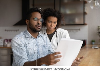 Focused Stressed Young Diverse Man Woman Family Couple Looking Through Paper Correspondence, Feeling Dissatisfied Reading Letter With Bad News, Bank Loan Rejection Notification Or Eviction Letter.