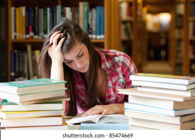 Focused Student Surrounded By Books In A Library