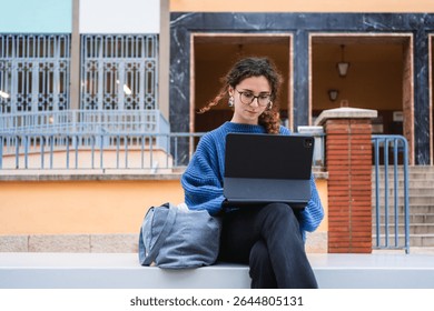 Focused student using digital tablet for online learning, enjoying fresh air and modern campus facilities