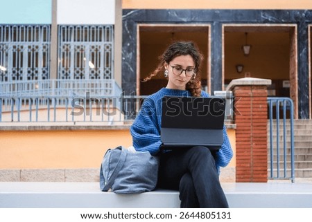 Focused student using digital tablet for online learning, enjoying fresh air and modern campus facilities