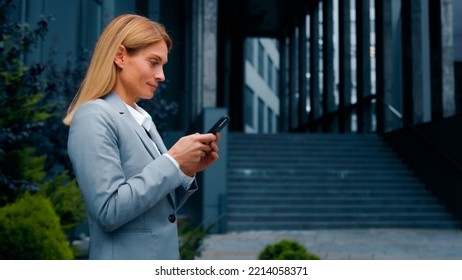 Focused Successful Businesswoman Walking Outdoors Holding Smartphone Writing Email Message Communicating With Friend Or Client On Social Media Using Mobile Phone Making Order In Online Store Side View