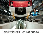 A focused technician with a tablet is inspecting a modern train in an industrial maintenance facility.