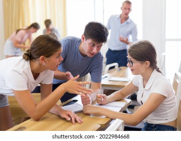 Focused Teenagers Working In Small Groups During Lesson At College, Discussing Assignment Given By Teacher. Active Learning Concept