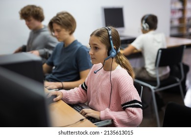 Focused ten-year-old schoolgirl wearing headphones, engaged at school at a informatics lesson in the classroom, sitting at ..a computer