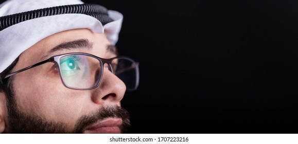 Focused and thoughtful Arab man in dark. Businessman working late. Student studying at night. Close up of glasses of confident Arabic young male. isolated on black background. - Powered by Shutterstock