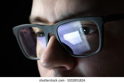 Focused and thoughtful man. Coder, programmer or developer using laptop in dark. Businessman working late. Student studying at night. Close up of glasses with reflection of computer screen.