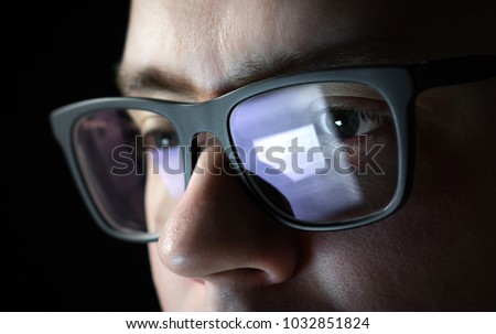 Focused and thoughtful man. Coder, programmer or developer using laptop in dark. Businessman working late. Student studying at night. Close up of glasses with reflection of computer screen.