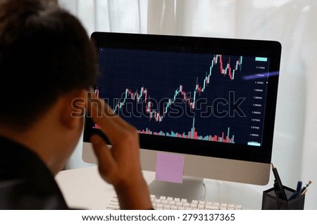 A focused trader studies a volatile forex candlestick chart on a computer monitor, conveying stress and concentration, ideal for finance and investment content.