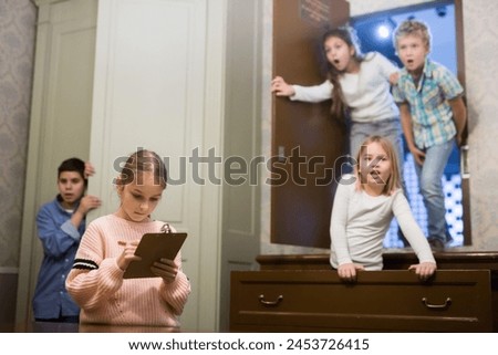 Focused tween girl having fun with her friends in quest room, trying to solve riddles
