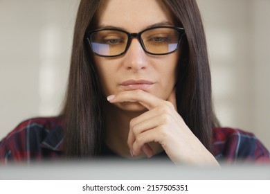 Focused Ukrainian woman in glasses working on laptop. Young programmer female doing work on notebook. Stock photo of white female person works on personal computer. Royalty free image of free lancer 
