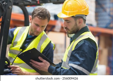 Focused Warehouse Workers Talking Together In Warehouse