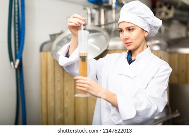 Focused woman brewer controlling process of craft beer production in small brewery, measuring alcoholic content in beverage with hydrometer - Powered by Shutterstock