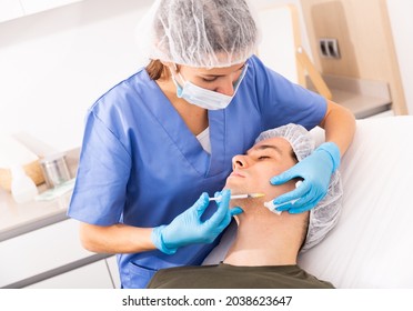 Focused Woman Cosmetologist Giving Beauty Injections For Face Skin Tightening For Male Client In Aesthetic Medicine Office