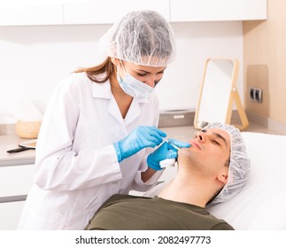 Focused Woman Cosmetologist Giving Beauty Injections For Face Skin Tightening For Male Client In Aesthetic Medicine Office